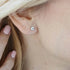 Close-up of an ear wearing a diamond stud earring with a hand holding the hair.