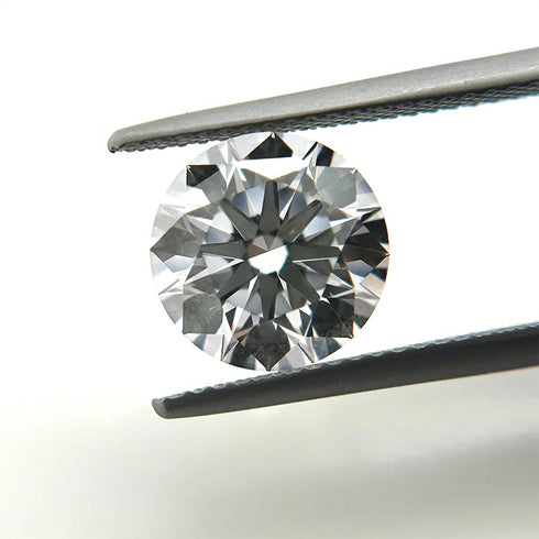 Round diamond held between tweezers on a white background
