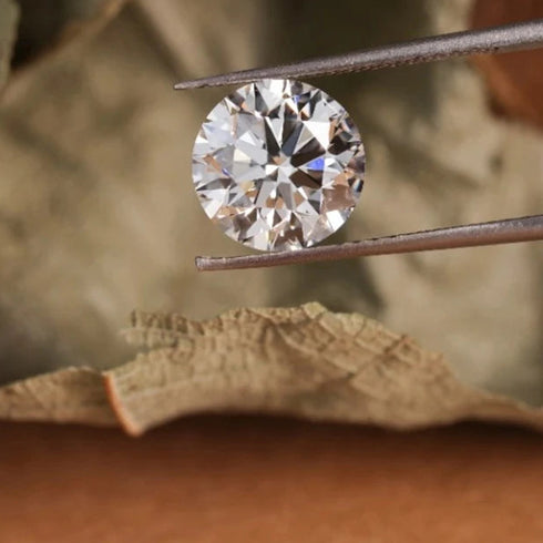 Diamond held by tweezers on a leafy background